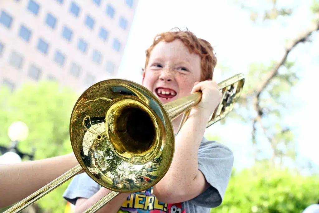 Boy playing a trombone outdoors.